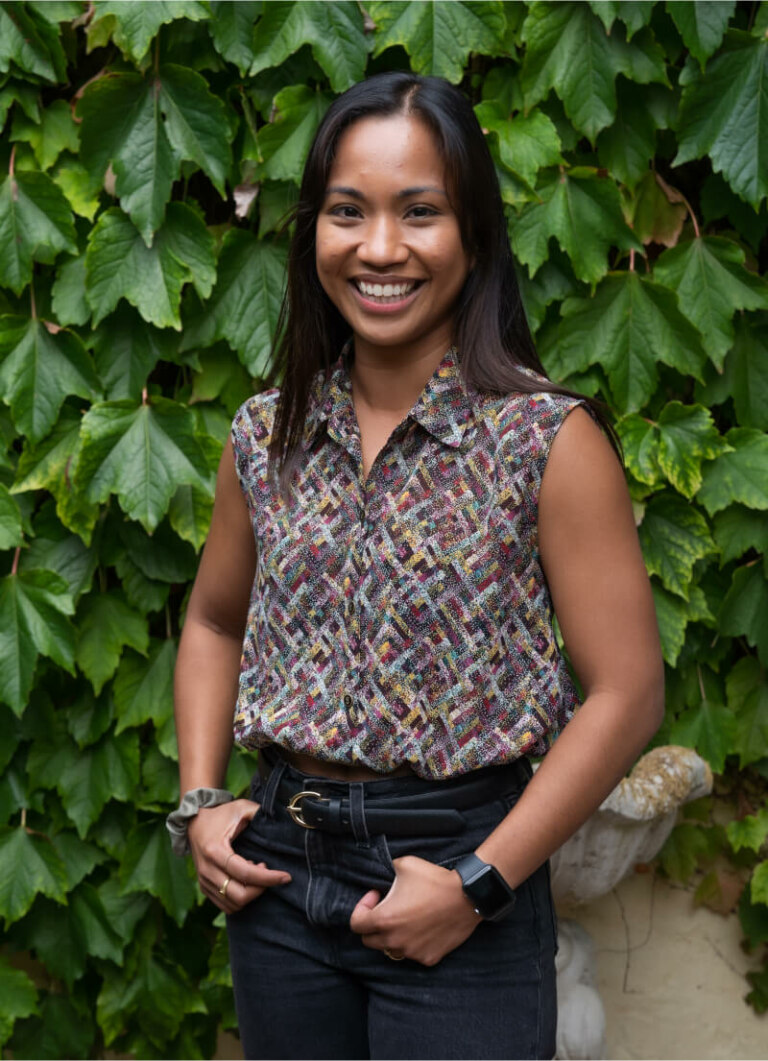 A woman smiling in front of a wall of ivy at Patrice Ventura's garden.