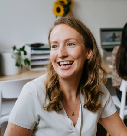 A smiling woman sitting at a desk in an office.