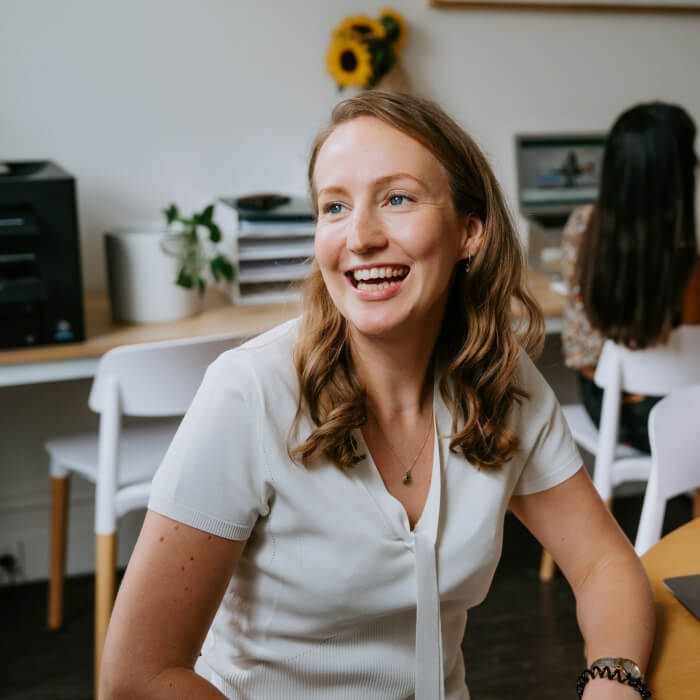 A smiling woman sitting at a table in an office.