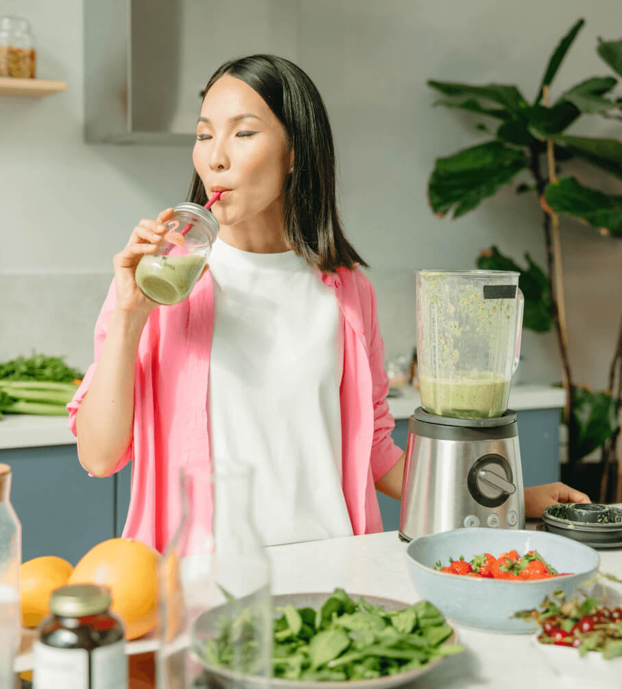A woman drinking a smoothie in the kitchen suggested by Dietician