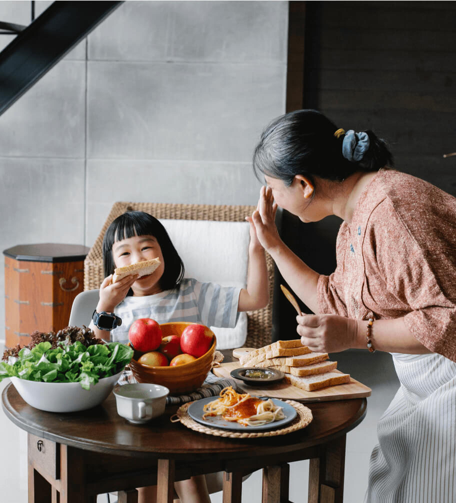 A nutritionist observing a mother and daughter eating food at a table.