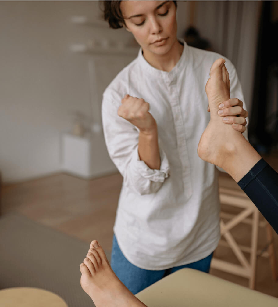 A professional providing podiatry services by giving a foot massage to a woman.