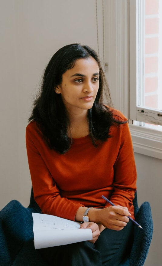 A physiotherapist sitting in a chair and holding a notebook.