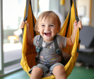 A baby is sitting in a yellow swing.
