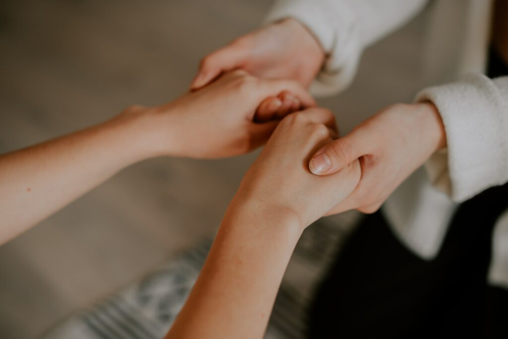 A woman, acting as a support coordinator, is holding another parent's hand.