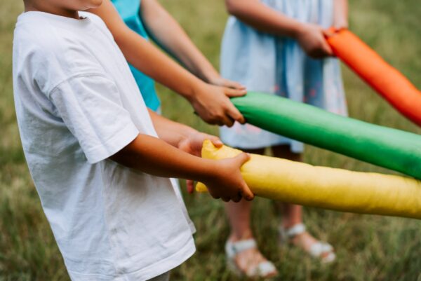 A group of children engaged in play, using colored sticks to develop their social skills in a field.